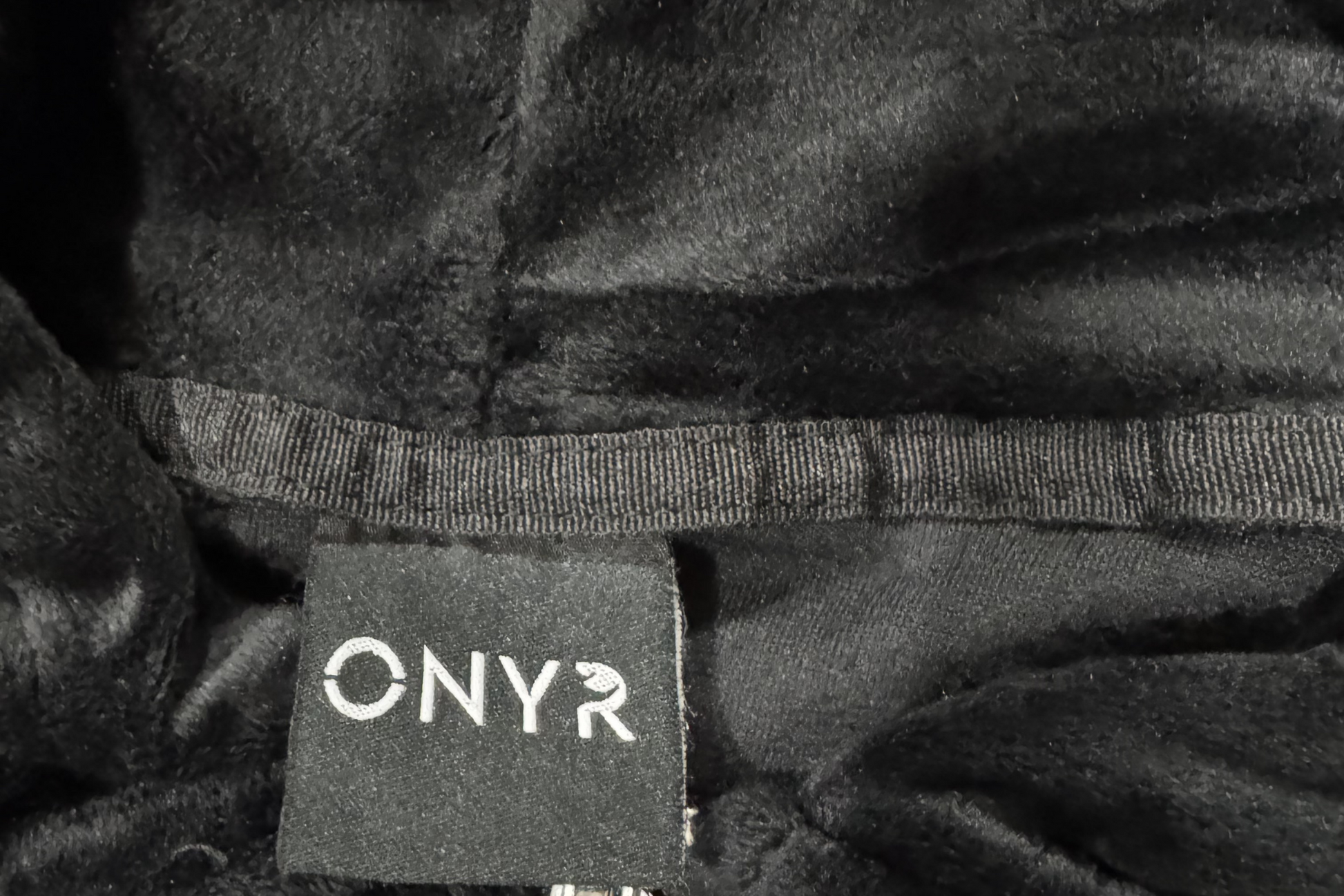 Close-up of a dark textured fabric with a 'ONYR' label.